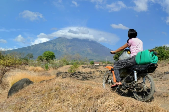 Une femme traverse en moto un paysage dominé par le mont Agung qui menace d'entrer en éruption, ce qui a provoqué l'évacuation de 75.000 habitants, à Bali le 26 septembre 2017