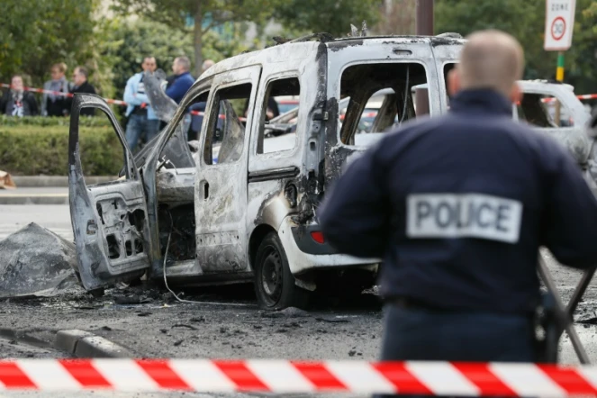 Un policier devant la carcasse d'un véhicule de police incendié à  Viry-Chatillon le 8 octobre 2016 