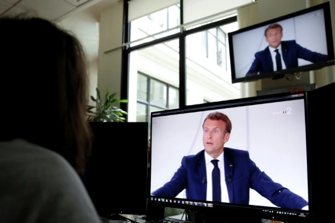 Une femme regarde une intervention télévisée du président français Emmanuel Macron le 14 juillet 2020 à Paris