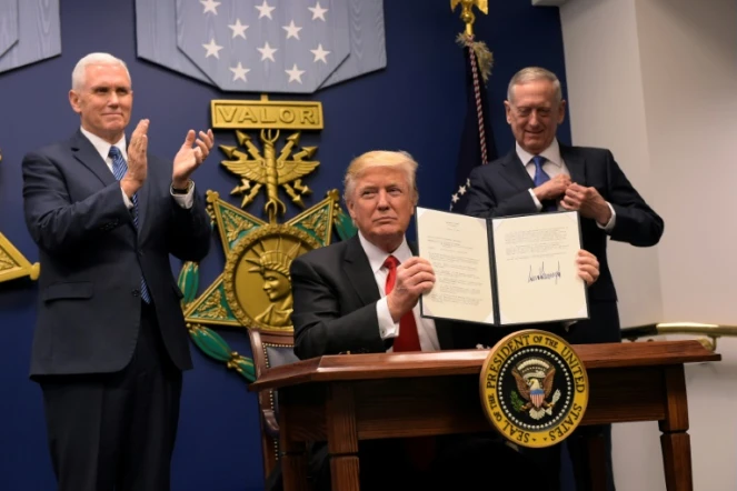 Le président américain Donald Trump signe un décret lors de la cérémonie d'investiture du secrétaire américain à la Défense James Mattis (d) en présence du vice-président Mike Pence (g), le 27 janvier 2017 au Pentagone, à Washington