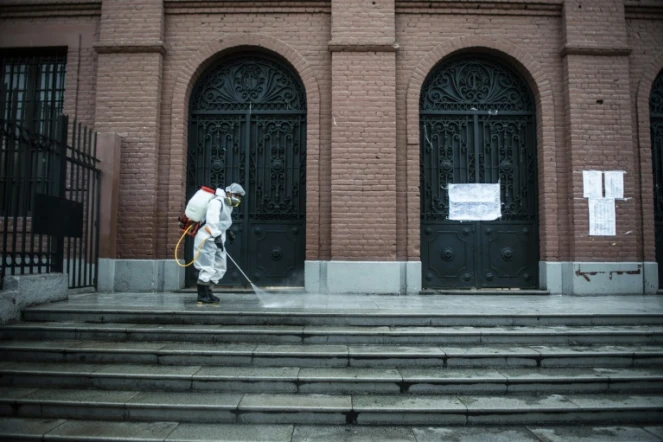 Un employé désinfecte les abords d'un bureau de vote à la veille du premier tour des élections présidentielles et législatives, à Lima le 10 avril 2021
