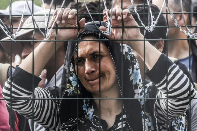 Une femme bloquée derrière la clôture de barbelés le 16 septembre 2015 à Horgos à la frontière entre la Hongrie et la Serbie 