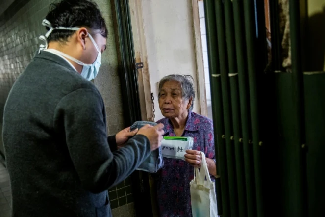 L'élu local pro-démocratie Eason Chan distribue des masques et produits d'hygiène dans un immeuble à Hong Kong le 14 mars 2020