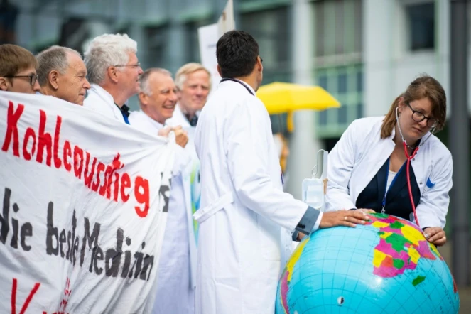 Deux médecins de l'organisation "Doctors For Future" ausculent une Terre en baudruche lors d'une manifestation pour la protection du climat en marge d'un congrès de médecins à Munster (nord-ouest de l'Allemagne), le 28 mai 2019