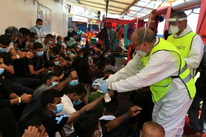 Un médecin italien distribue des bracelets numérotés à des migrans secourus sur le navire humanitaire Ocean Viking, le 5 juillet 2020 en Méditerranée   