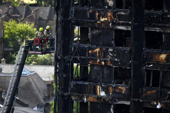 Des pompiers sur une grande échelle inspectent les décombres de la tour Grenfell à Londres le 16 juin 2017