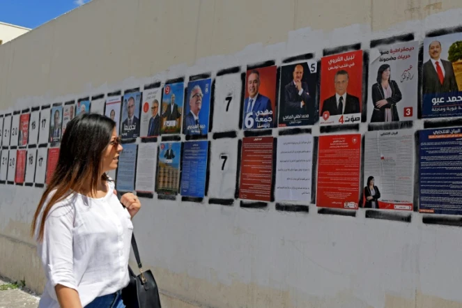 Une Tunisienne passe devant des affiches de campagne des candidats à la présidentielle, le 7 septembre 2019 à Tunis