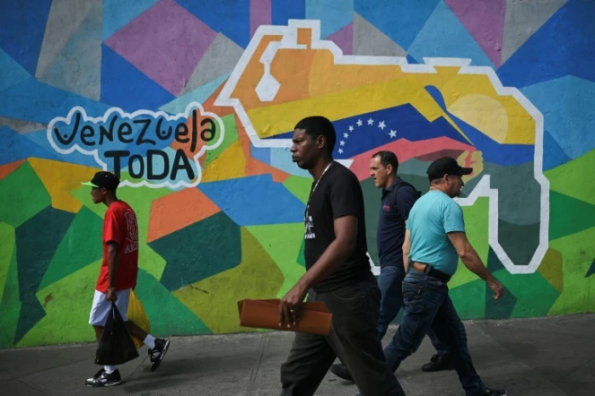 Des personnes passent devant une fresque murale faisant campagne pour un référendum demandant aux Vénézuéliens d'envisager l'annexion de la région de l'Essequibo administrée par le Guyana voisin, à  Caracas, le 28 novembre 2023