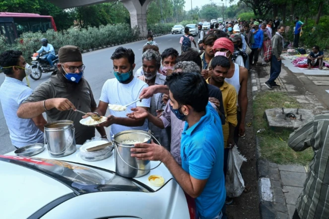 Des Indiens sans domicile fixe,  notamment des travailleurs journaliers, font la queue pour une distribution de nourriture à New Delhi le 20 mai 2021
