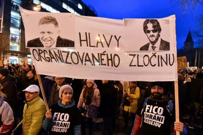 Des manifestants brandissent une banderole avec des portraits du Premier ministre Robert Fico (D) et du ministre de l'Intérieur Robert Kalinak et le slogan "chefs du crime organisé", pendant une manifestation à Bratislava, le 9 mars 2018