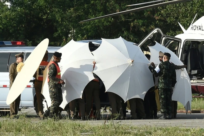 Des policiers et des militaires recouvrent une civière avec des parapluies le 9 juillet 2018 alors que se poursuivent les opérations de sauvetage pour de jeunes footballeurs coincés dans une grotte en Thaïlande 