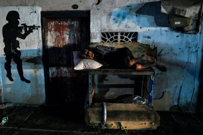 Un homme dort devant sa maison pendant une coupure de courant à Colombo, le 30 mars 2022 au Sri Lanka