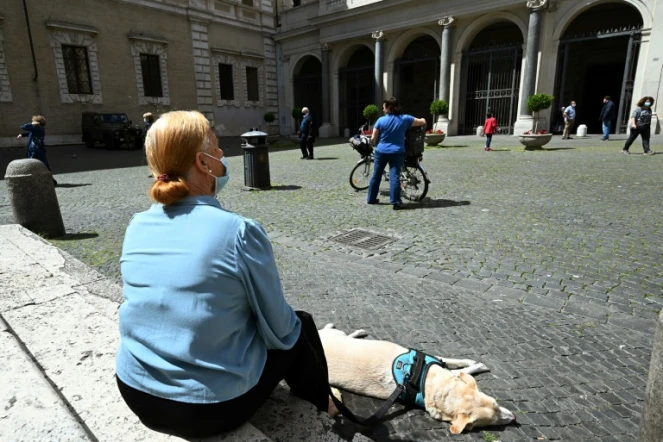 Une femme et son chien se reposent sur la place Santa Maria à Trastevere, à Rome, le 3 mai 2020.
