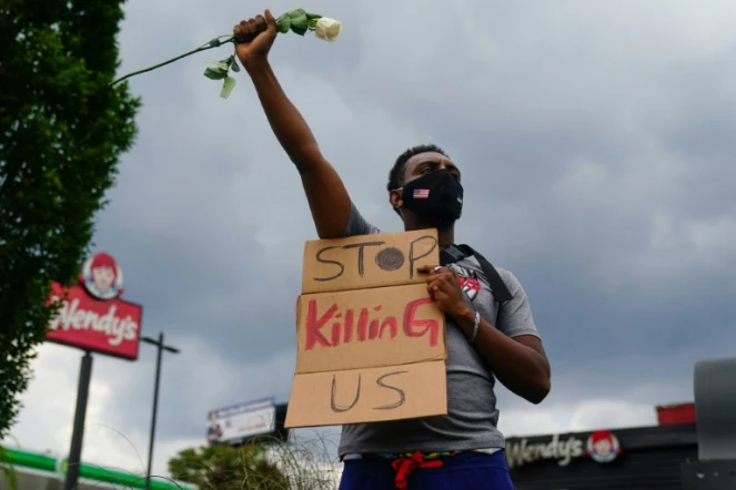 Un manifestant tient une pancarte implorant "arrêtez de nous tuer", devant le restaurant près duquel est mort l'avant-veille Rayshard Brooks, un Afro-Américain tué par un policier blanc, à Atlanta le 14 juin 2020