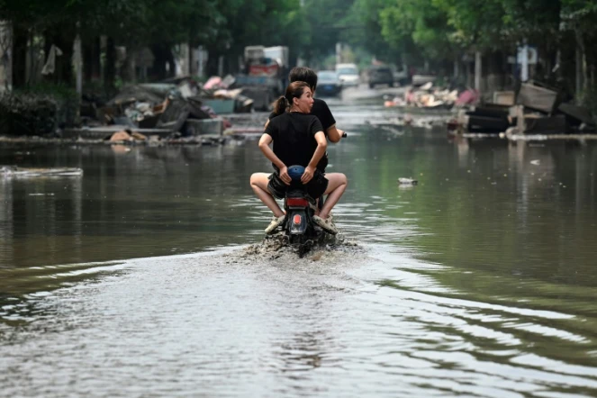 Des habitants de Zhuozhou en scooter dans l'eau, après de fortes pluies qui ont provoqué des inondations dans la province du Hebei, le 9 août 2023

