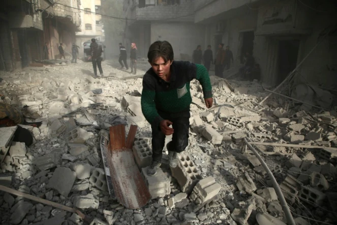 Un jeune syrien cours dans une rue d'une localité dans l'enclave rebelle de la Ghouta orientale, après un bombardement du régime, le 8 février 2018