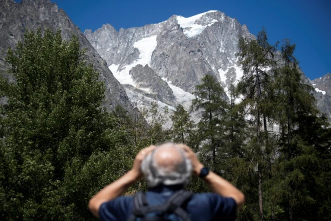 Un homme observe avec des jumelles le glacier de Planpincieux à Courmayeur, le 6 août 2020 au Val Ferret, en Italie