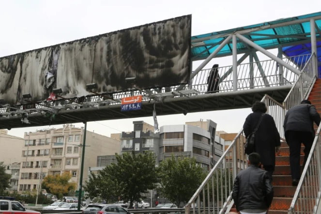 Image prise à Téhéran le 19 novembre 2019, montrant un grand panneau publicitaire au-dessus d'une autoroute urbaine incendié.  