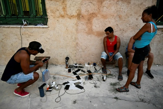 Des habitants rechargent leurs téléphones portables à La Havane pendant une panne de courant à Cuba, le 15 mars 2025