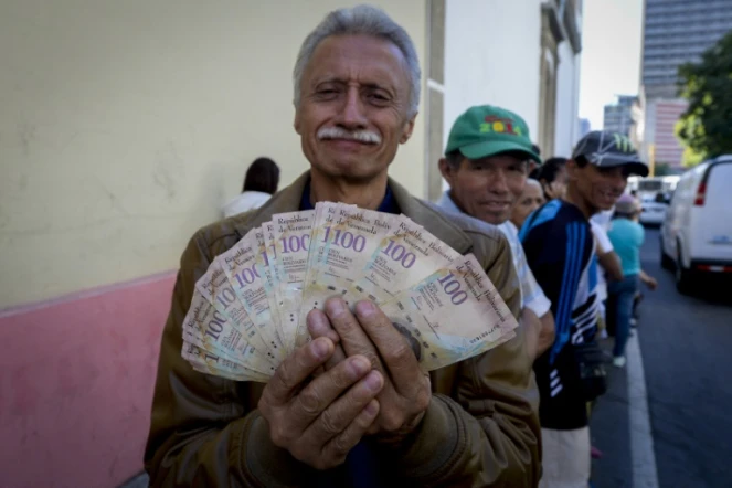 Un homme montre ses billets de 100 bolivars en attendant de pouvoir les échanger à la banque centrale du Venezuela à Caracas, le 16 décembre 2016