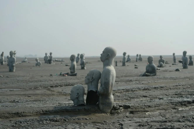 Vue en date du 28 mars 2016 de sculptures de personnes à moitié enterrées dans le volcan de boue qui a surgi de terre le 29 mai 2006 à Sidoarjo