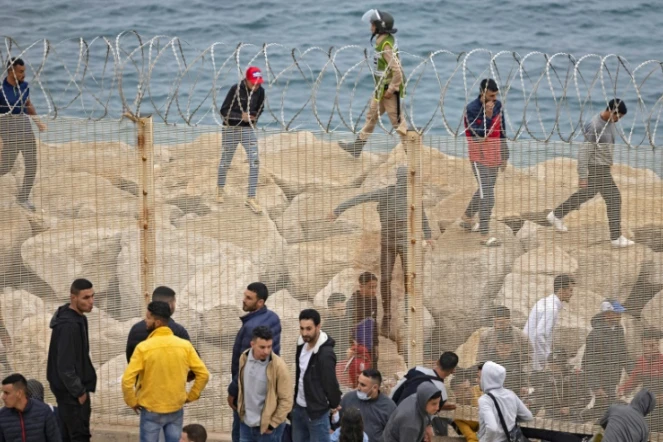 Des migrants marocains passent à travers une barrière de la ville de Fneideq vers l'enclave espagnole de Ceuta le 18 mai 2021