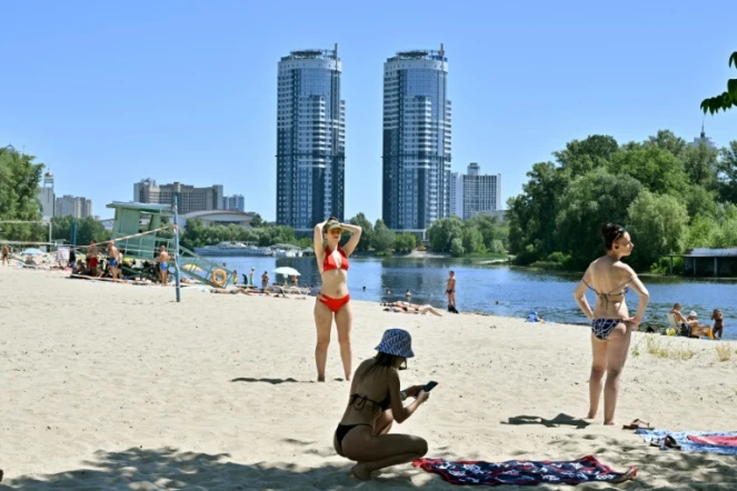 Des femmes prennent le soleil sur les rives sablonneuses du fleuve Dniepr à Kiev, le 2 juillet 2022