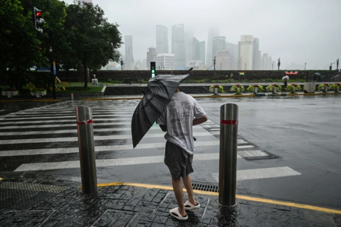 Un homme tente de se protéger du typhon Bebinca avec son parapluie, le 16 septembre 2024 à Shanghai