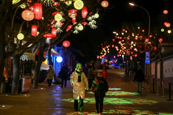 Des piétons dans une rue décorée de lanternes  à la veille de la nouvelle année lunaire du serpent à Pékin, le 28 janvier 2025