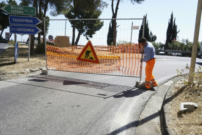 Un ouvrier installe une barrière de signalisation de chantier sur la chaussée, le 4 mai 2017 à Taormina