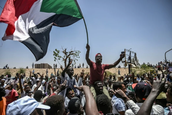 Des manifestants brandissent le drapeau soudanais lors d'un sit-in devant le QG de l'armée à Khartoum, le 22 avril 2019