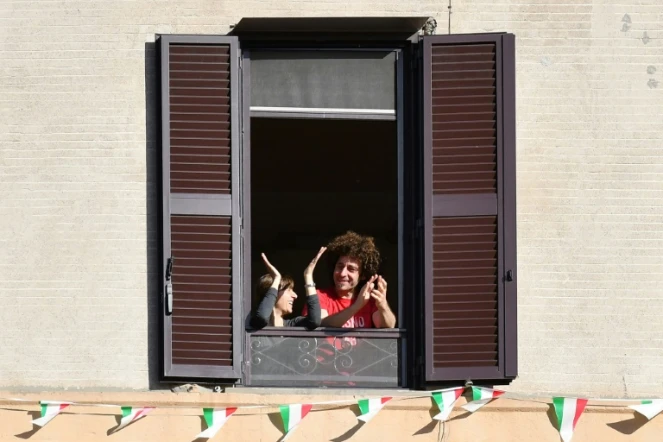 Des Italiens applaudissent depuis leur fenêtre l'assouplissement du confinement, à Rome le 3 mai 2020
