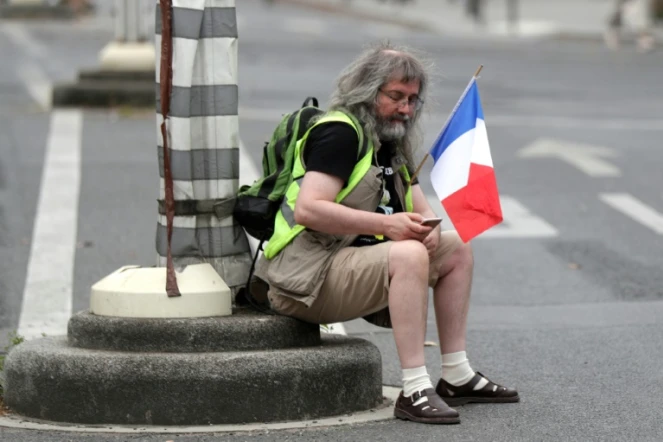 Un homme tient un drapeau français lors d'une manifestation anti-pass sanitaire le 21 août 2021 à Paris 
