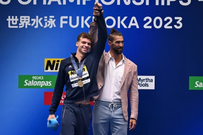 Le Français Leon Marchand félicité par l'Américain Michael Phelps, après lui avoir ravi le record du monde du 400 m 4 nages, aux Mondiaux de natation de Fukuoka, le 23 juillet 2023 