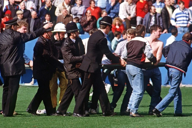 Des policiers transportent un supporteur blessé dans le stade de Hillsborough, le 15 avril 1989 à Sheffield, au Royaume-Uni
