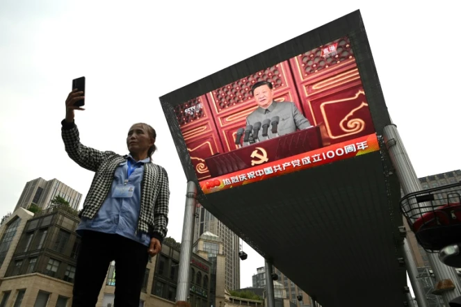 Une femme prend un selfie devant un écran sur lequel est retransmis le discours du président chinois Xi Jinping à l'occasion du centenaire du parti communiste chinois, à Pékin le 1er juillet 2021