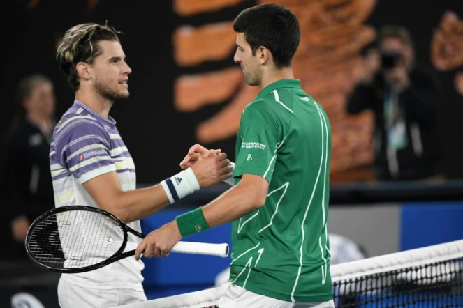 Le Serbe Novak Djokovic (d) serre la main de l'Autrichien Dominic Thiem après l'avoir battu en finale de l'Open d'Australie, le 2 février 2020 à Melbourne