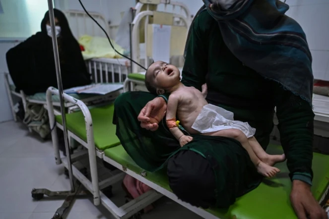 Une mère tient son enfant souffrant de malnutrition, mis sous perfusion dans une clinique de Médecins sans Frontières à Hérat, en Afghanistan, le 22 novembre 2021 
