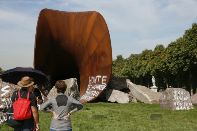 Des visiteurs s'arrêtent devant une des  ?uvres de Anish Kapoor vandalisée par des tags antisémites, dans les jardins du Château de Versailles le 11 septembre 2015