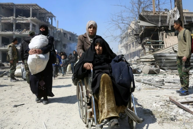 Une syrienne en fauteil roulant évacue la localité de Jisrine dans la Ghouta orientale, en direction de zones sous contrôle gouvernemental, le 17 mars 2018