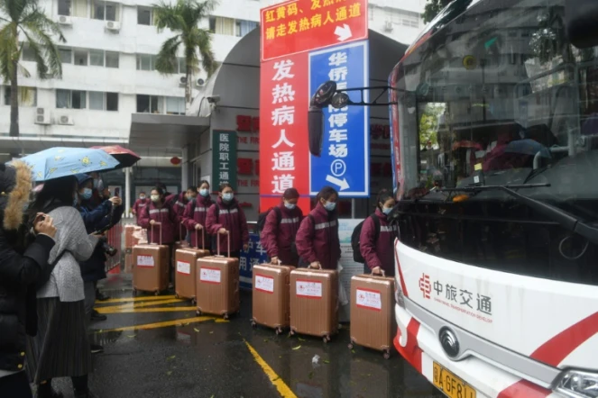 Des personnels médicaux montent à bord d'un bus à destination de Hong Kong pour apporter leur aide face à l'augmention des cas de Covid-19, le 19 février 2022 à Canton, dans le sud de la Chine