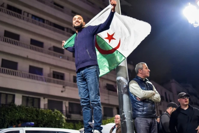Un Algérien brandit le drapeau national lors de rassemblements dans les rues de la capitale Alger, le 11 mars 2019 au soir