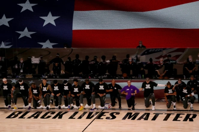 Membres des Los Angeles Lakerset des LA Clippers agenouillés devant le mot d'ordre "Black lives matter" et durant l'hymne américain avant leur match de NBA, le 30 juillet 2020 à Lake Buena Vista (Floride)