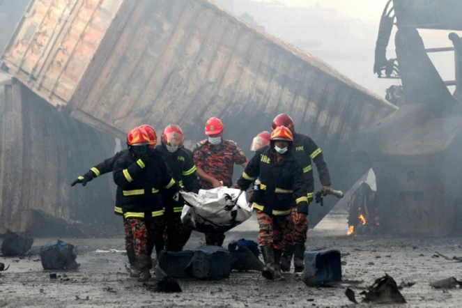 Des pompiers portent le corps d'une victime d'un incendie dans un entrepôt de conteneurs, le 5 juin 2022 à Sitakunda, au Bangladesh