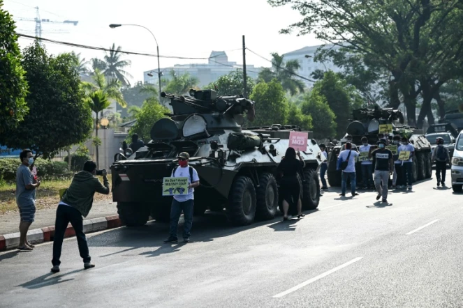 Des manifestants pro-démocratie se rassemblent près de véhicules blindés de l'armée à Rangoun, le 15 février 2021