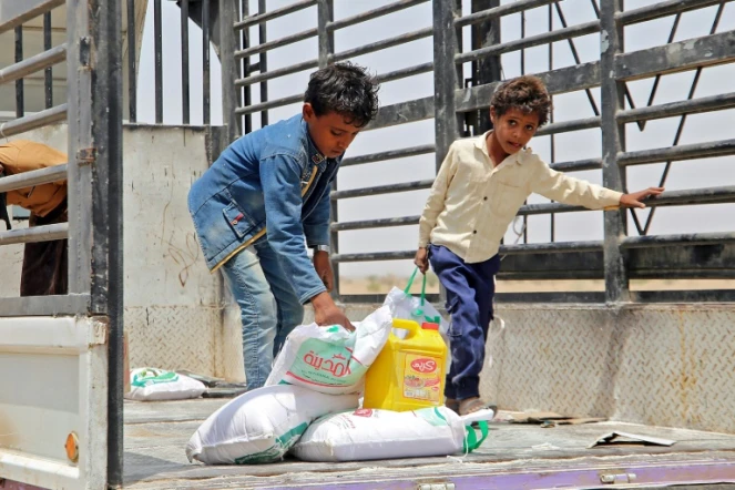 Des enfants portent des rations alimentaires dans un camp de déplacés, dans la province de Hodeida, le 29 mars 2022 au Yémen