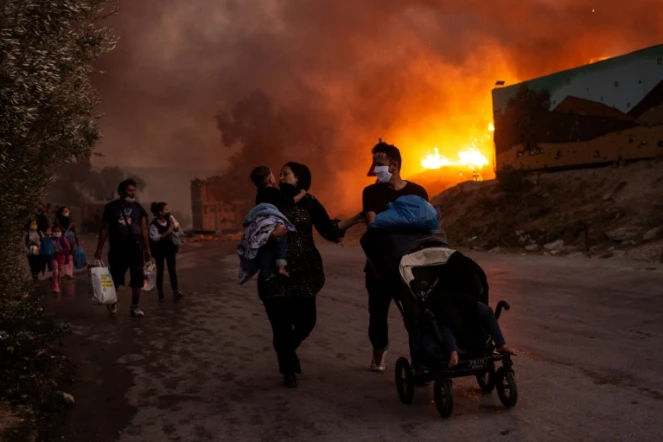 Une famille de migrants fuit le camp de Moria incendié, le 9 septembre 2020 à Lesbos, en Grèce