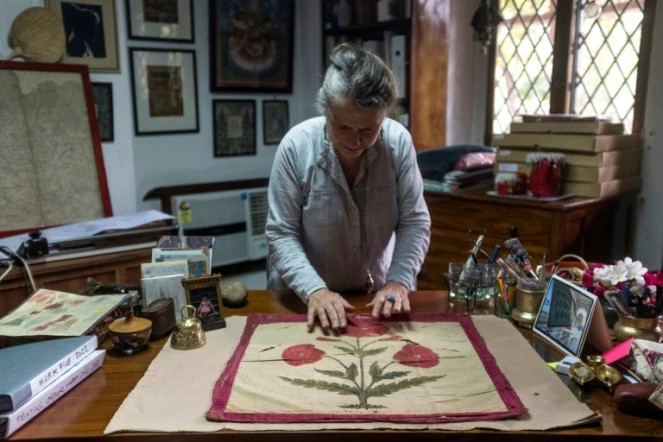 Brigitte Singh étend sur son bureau un carré d'étoffe moghol du XVIIe siècle, orné d'un grand pavot rouge, le 2 juin 2022 à Amber, dans l'Etat du Rajasthan, en Inde
