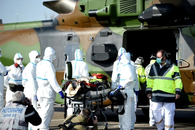 Des équipes médicales transportent un patient contaminé par le Covid-19 pour l'évacuer à bord d'un hélicoptère vers l'hôpital d'Essen, en Allemagne, le 28 mars 2020 sur le parking du CHR de Metz