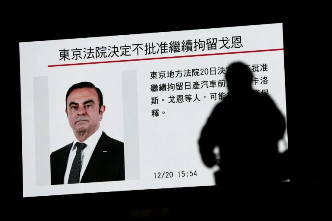 Un passant marche devant un écran de télévision diffusant une émission parlant de Carlos Ghosn à Tokyo le 20 décembre 2018